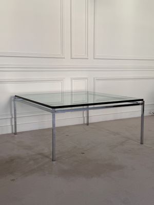 an image of a glass and chrome coffee table in a white room