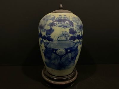 un vase bleu et blanc posé sur un socle, sur une table