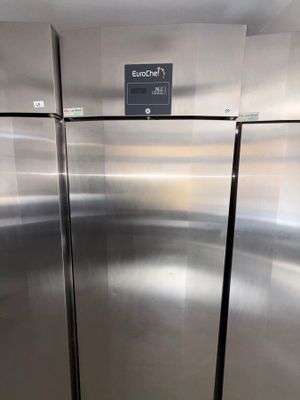 two stainless steel refrigerators in a kitchen with a sign on the door