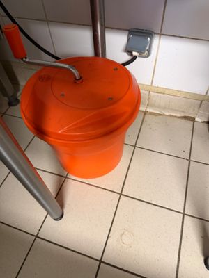 un seau orange posé à côté des toilettes dans une salle de bains
