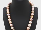 a pink pearl necklace on a mannequin with a gold clasp