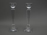 pair of clear glass candlesticks sitting on top of a table