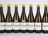 six bouteilles de vin sont alignées sur une surface blanche