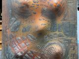 une sculpture en bronze représentant un visage, exposée dans une vitrine