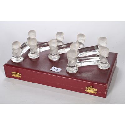 six figurines en verre transparent posées sur un socle en bois rouge
