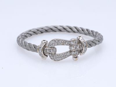 un bracelet en argent muni d'une boucle et orné de diamants sur fond blanc