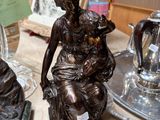 a statue of a woman sitting on a table next to a teapot