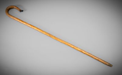 an old wooden walking stick with a black handle on a gray background