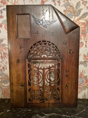une vieille horloge en bois ornée d'un oiseau, posée sur une table