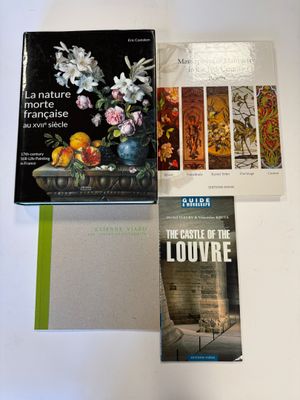 trois livres posés sur une table sur laquelle se trouve un vase de fleurs