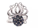 un gros plan sur une bague en forme de pieuvre ornée de pierres bleues et blanches