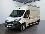 La camionnette blanche est garée dans une grande pièce au sol noir.