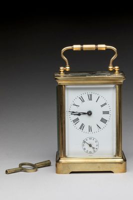 an image of a small brass clock with a key on a table
