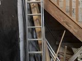 une échelle appuyée contre un mur, à côté d'un tas de vieilleries