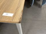a wooden table with white legs and a name tag on it