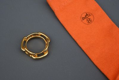 une cravate orange et une bague en or posées sur une table