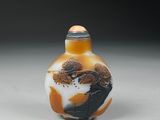 an orange and white glass snuff bottle sitting on top of a table