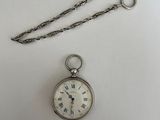 une montre de poche en argent à laquelle est suspendue une chaîne sur le côté