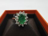 gros plan d'une bague avec une pierre verte entourée de diamants