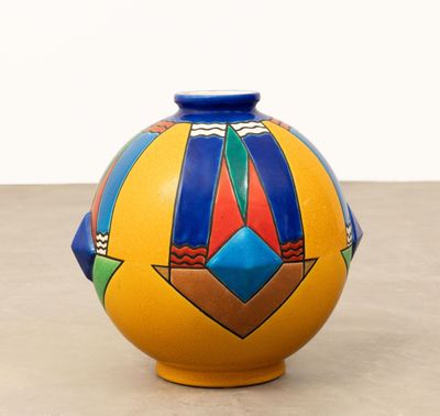 un vase jaune orné d'un motif bleu et rouge, posé sur une table
