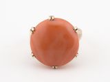 une image représentant une bague de couleur corail posée sur une surface blanche
