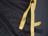 an old black coat with yellow trim and fringes on a black background