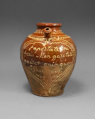 un vieux vase marron, orné d'une inscription, posé sur une table