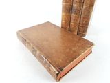 three old books sitting on top of each other on a white surface