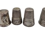 three antique thimbles are lined up on a white surface