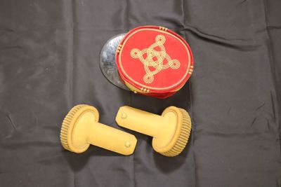 un pinceau jaune et un récipient rouge posés sur un tissu noir