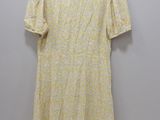 a yellow dress hanging on a hanger against a white wall