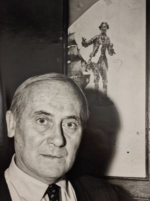 photographie en noir et blanc d'un homme en costume-cravate assis devant un tableau