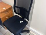 a black office chair next to a desk in a room
