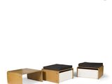 three wooden stools and a table with a black cushion