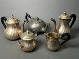 five silver teapots and two silver teapots on a table