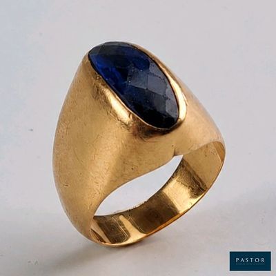 gros plan d'une bague en or avec une pierre bleue