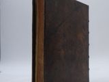 an old book with a brown cover sitting on top of a white table