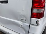 the rear end of a white truck with a dented tail end