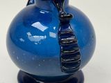 a blue glass vase with a black tie on it