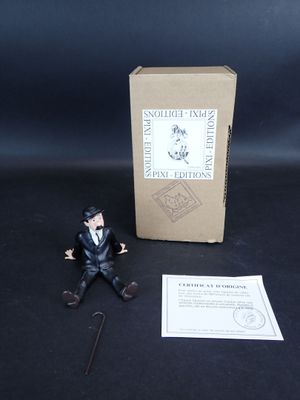 une petite figurine représentant un homme en costume assis à côté d'une boîte