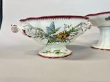 two white bowls with red trims and flowers on them