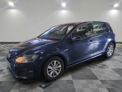 Une Volkswagen Golf bleue est garée dans une pièce au sol à carreaux.