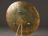 a gold clock on a stand on a gray surface