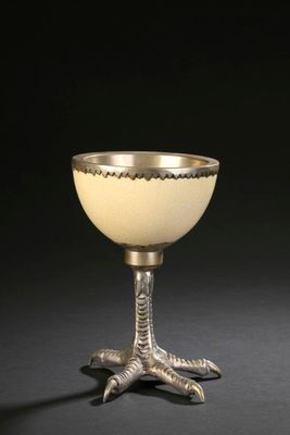 a silver cup with a bird foot on the base