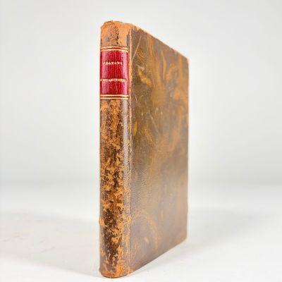 un vieux livre à la couverture rouge posé sur une surface blanche