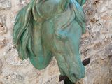 une statue représentant une tête de cheval sur un mur de pierre