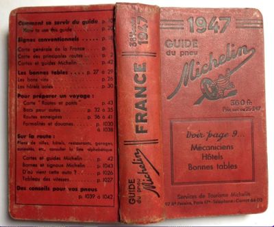 an old red book sitting on top of a table next to a white table