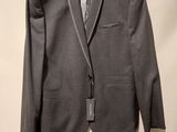 grey suit on a hanger in front of a white wall