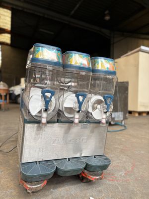 trois distributeurs de boissons gazeuses posés sur un chariot dans un entrepôt