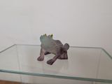 une figurine représentant une grenouille assise sur une table en verre